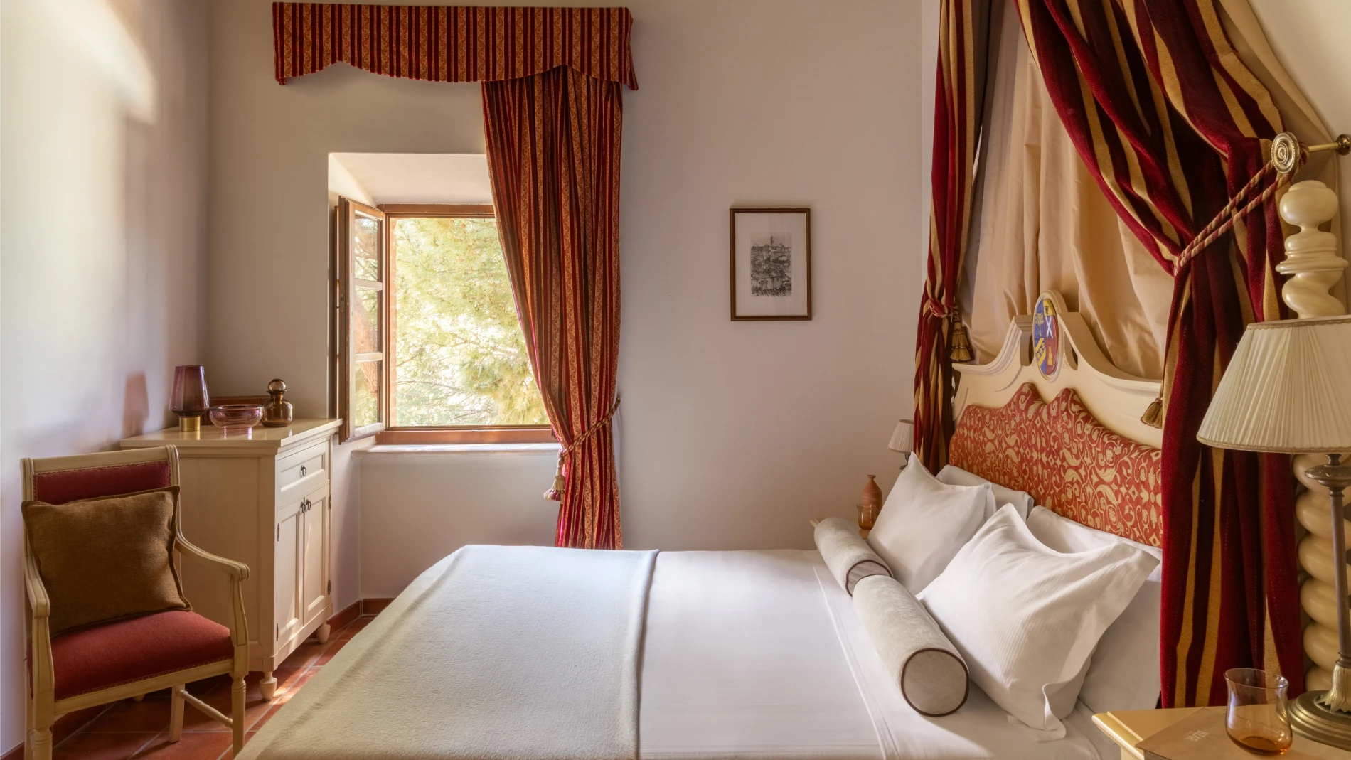Elegant room with canopy bed, red drapes and bright window in classic Tuscan style in Asciano - Castello di Leonina, BZAR hotels in Tuscany