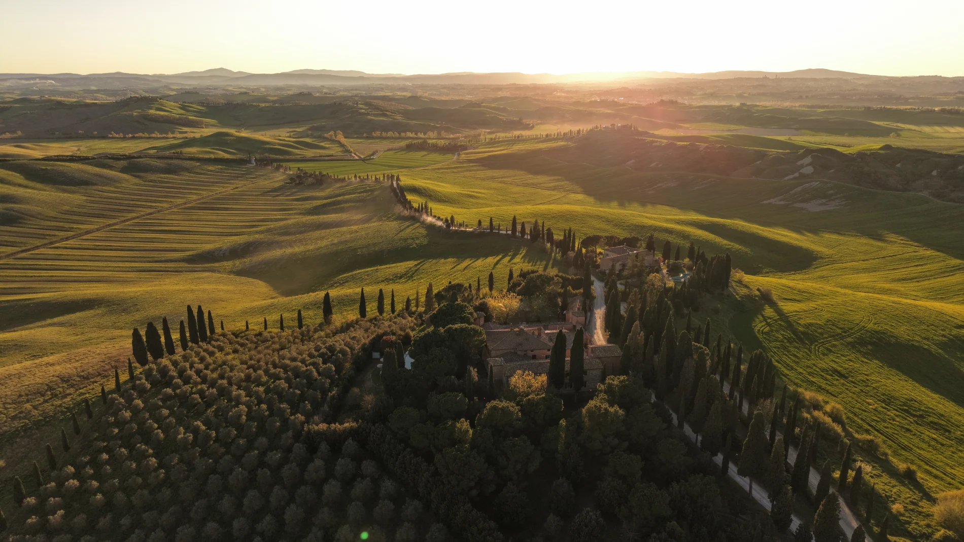Aerial sunset view of Castello di Leonina among cypress trees and rolling Crete Senesi hills in Tuscany - Castello di Leonina, BZAR hotels in Tuscany