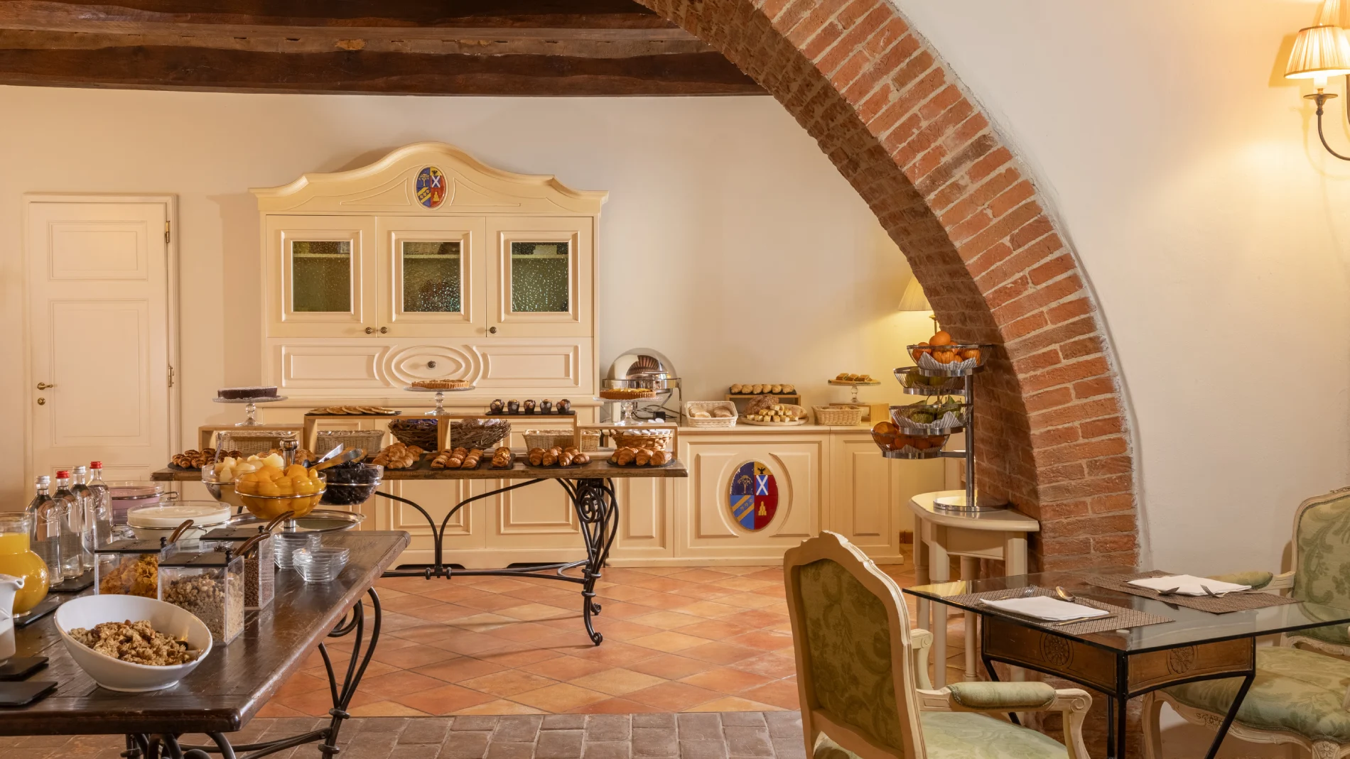 Breakfast room with sweet and savory buffet, classic furnishings and brick arches in a charming relais in Asciano - Castello di Leonina, BZAR hotels in Tuscany