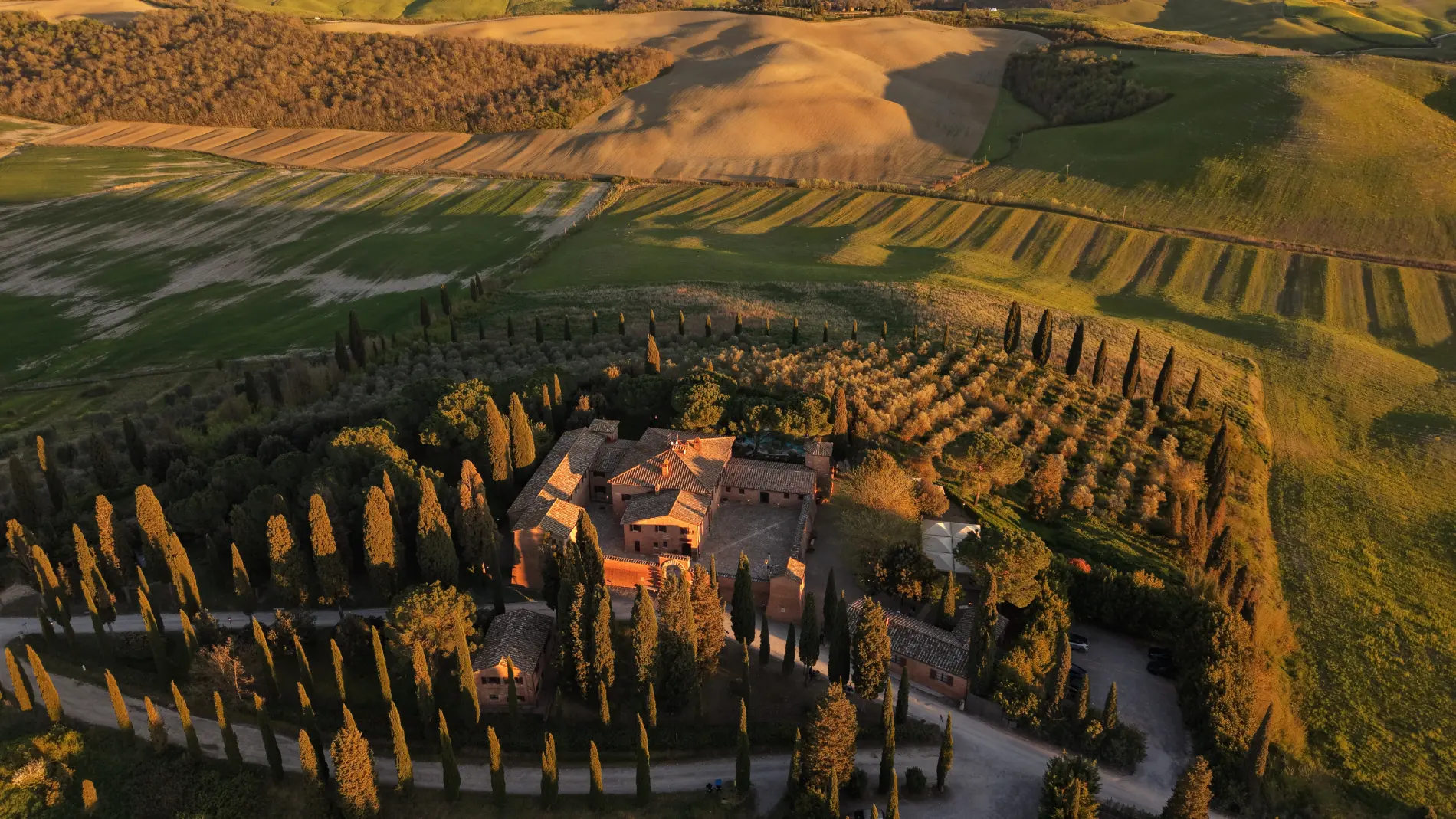 Vista aerea del Castello di Leonina tra cipressi, uliveti e colline delle Crete Senesi al tramonto - Castello di Leonina, BZAR hotels in Toscana