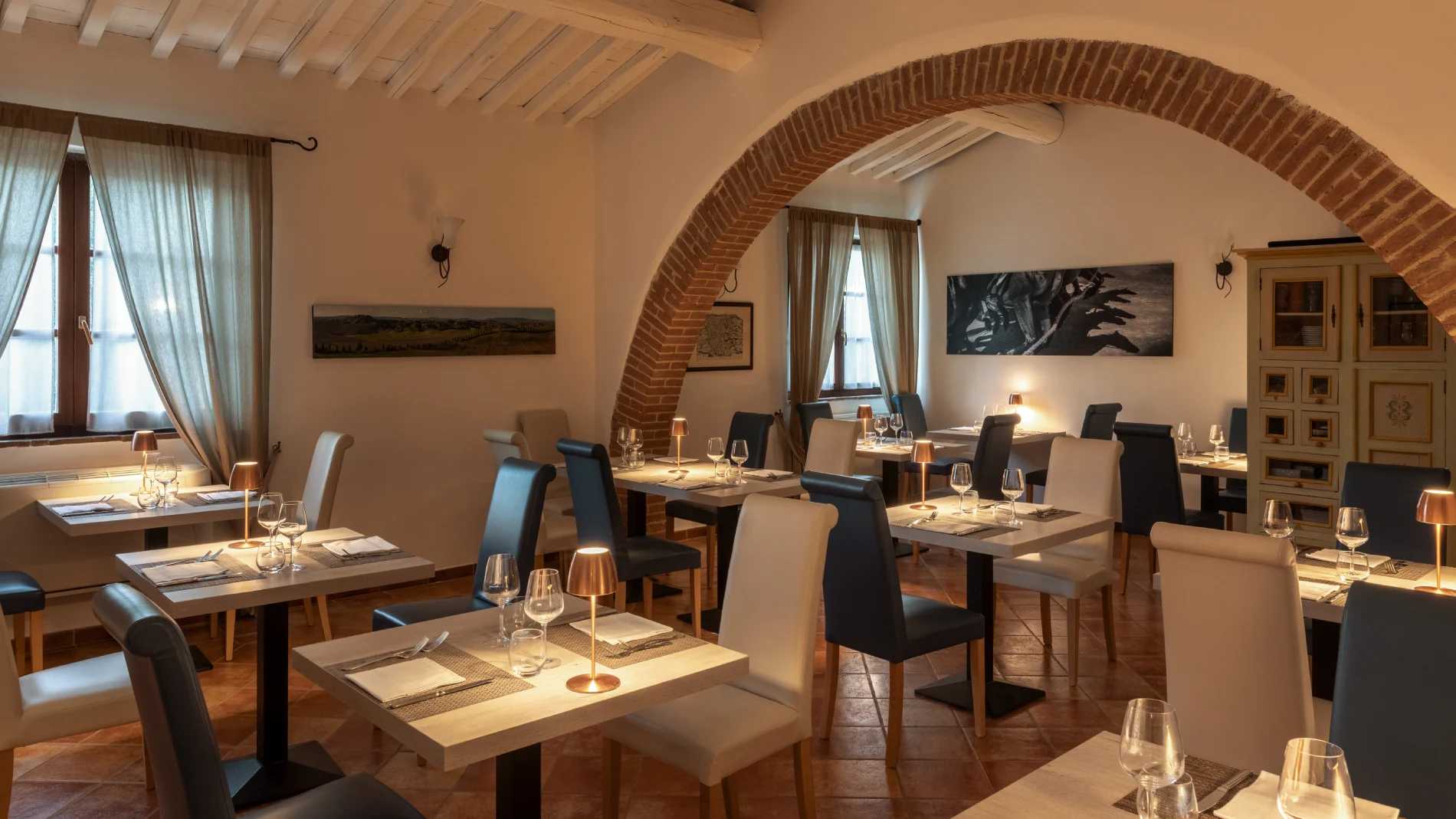 Indoor restaurant with elegant tables, soft lighting and brick arches in a refined setting in Asciano - Castello di Leonina, BZAR hotels in Tuscany