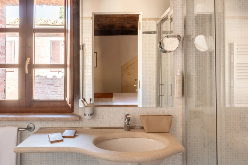 Elegant en-suite bathroom with shower, bright window and stone details in a charming hotel in Asciano Tuscany - Castello di Leonina, BZAR hotels in Tuscany