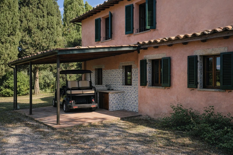 Esterno della villa con patio coperto, golf cart e dettagli rustici immersi nella natura delle Crete Senesi - Villa San Bartolomeo, BZAR hotels in Toscana