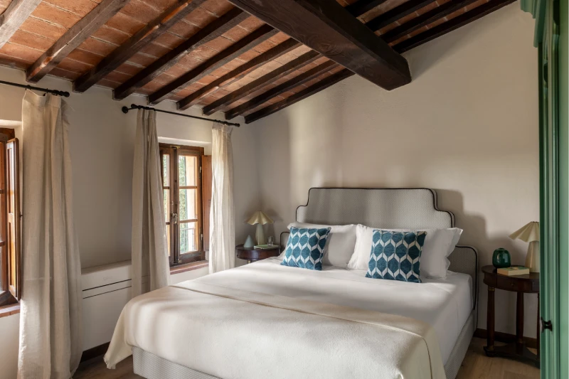 Camera matrimoniale della Villa Annex Adults Only con soffitto in cotto a travi e cuscini blu nelle Crete Senesi - Castello di Leonina, BZAR hotels in Toscana