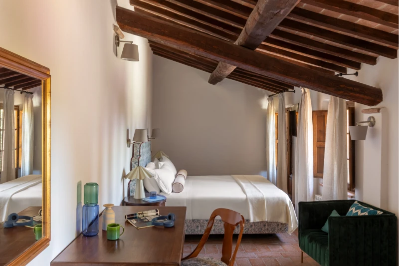 Camera con travi in legno a vista della Villa Annex Adults Only, scrivania e poltrona verde in stile toscano ad Asciano - Castello di Leonina, BZAR hotels in Toscana