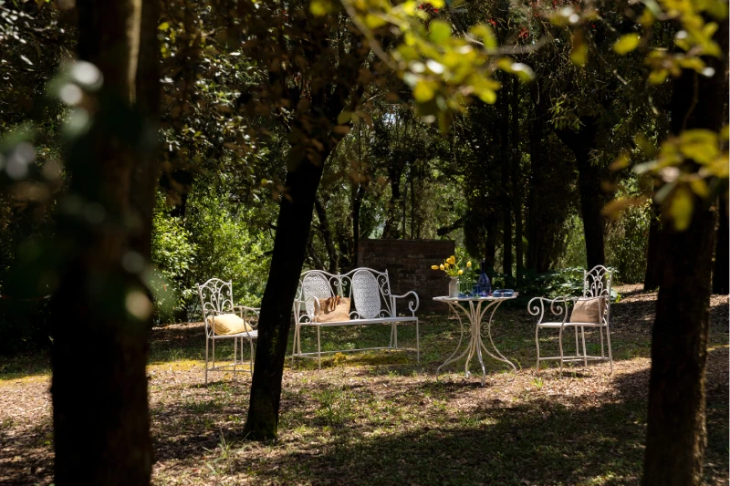 Giardino ombreggiato della Villa Annex Adults Only con sedute in ferro battuto tra gli alberi delle Crete Senesi - Castello di Leonina, BZAR hotels in Toscana